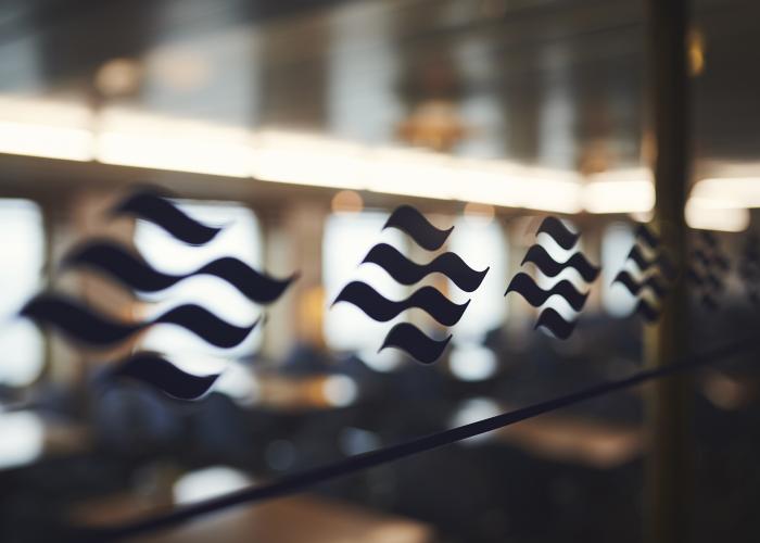 A navy blue wave Marine Atlantic logo emblem motif lines a window looking into one of the ferry's dining rooms.