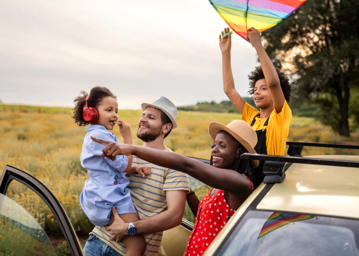 family stands beside car