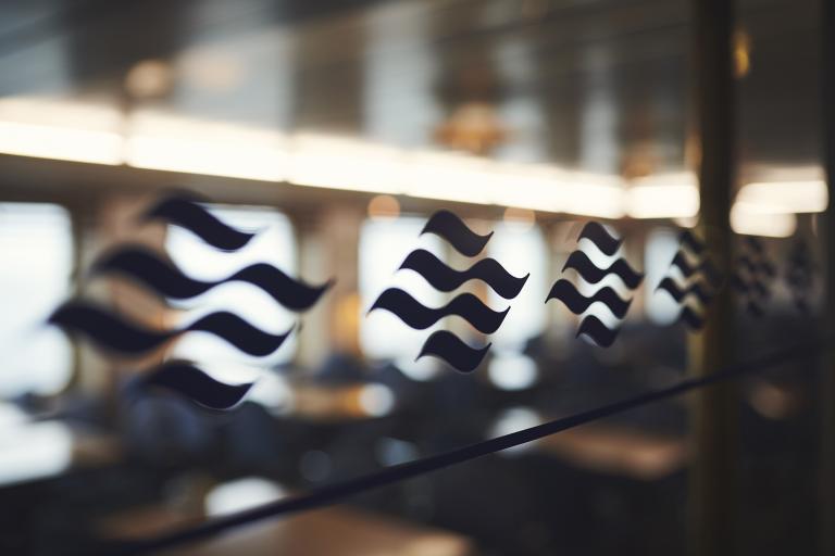 A navy blue wave Marine Atlantic logo emblem motif lines a window looking into one of the ferry's dining rooms.