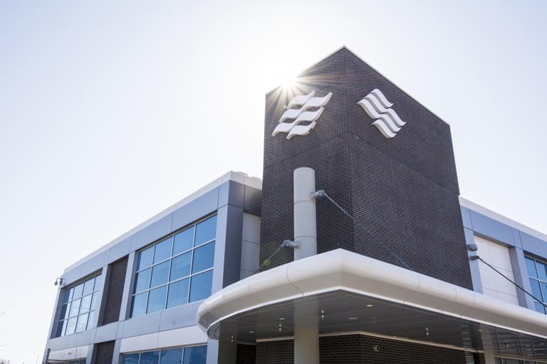 The sun shines down on the brick facade and Marine Atlantic wave logo of a modern looking office building/ferry terminal. 