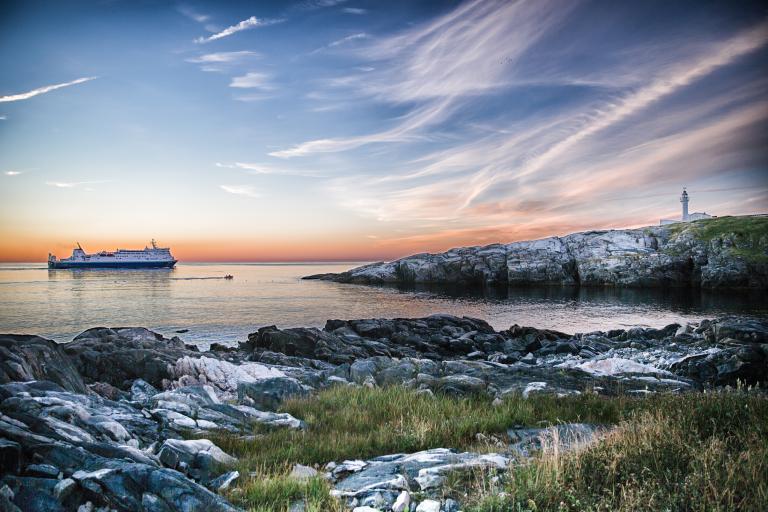 A Marine Atlantic ferry sails along the Avalon Peninsula at sunset towards the Cape Spear Lighthouse in Newfoundland. 
