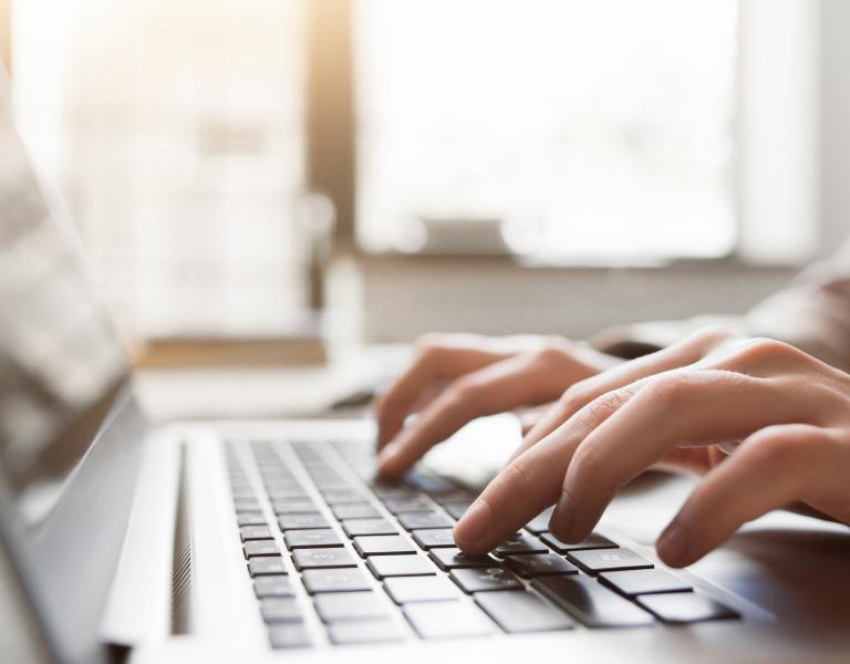 Fingers typing on laptop keyboard.