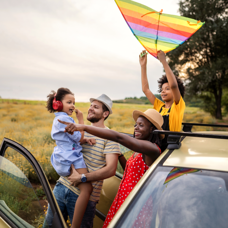 family stands beside car