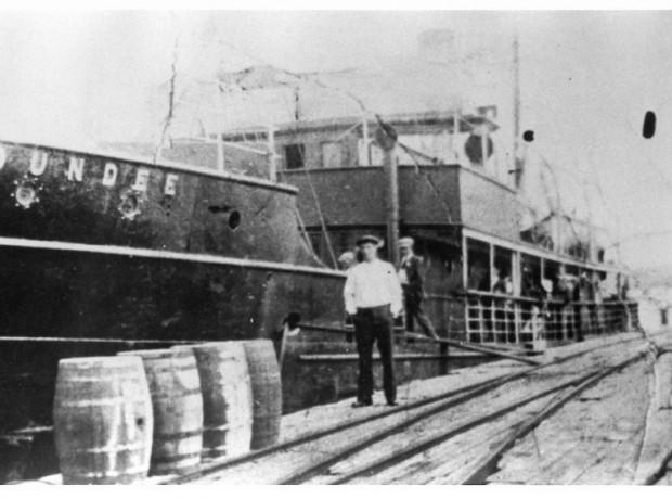 Image: black and white, crew member posing in front of the SS Dundee