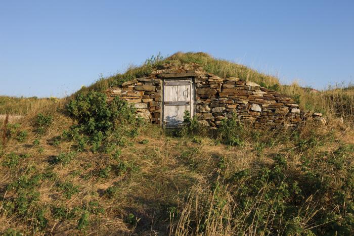 door surrounded by rocks in edge of grassy hill