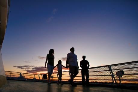 family walking on ferry deck at sunset