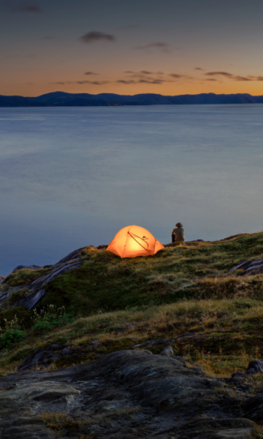 tent sitting on water's edge glows from inside