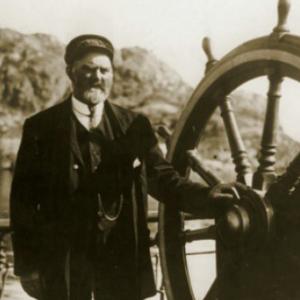 Old photo of a captain by the steering wheel of a ship