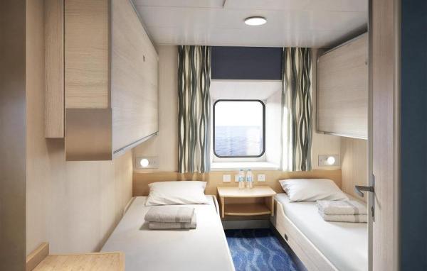 A cabin interior with two single beds, a shared nightstand, window with ocean view, and blue patterned carpet